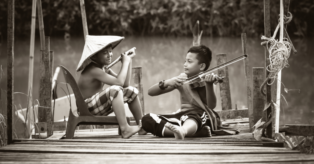 Children playing with instruments sat next to each other