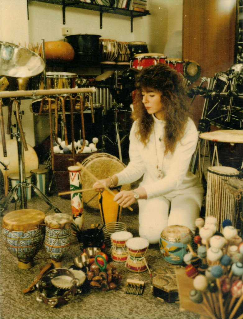 A colour photo of Evelyn at her home studio, playing a range of instruments, in the early 1990s