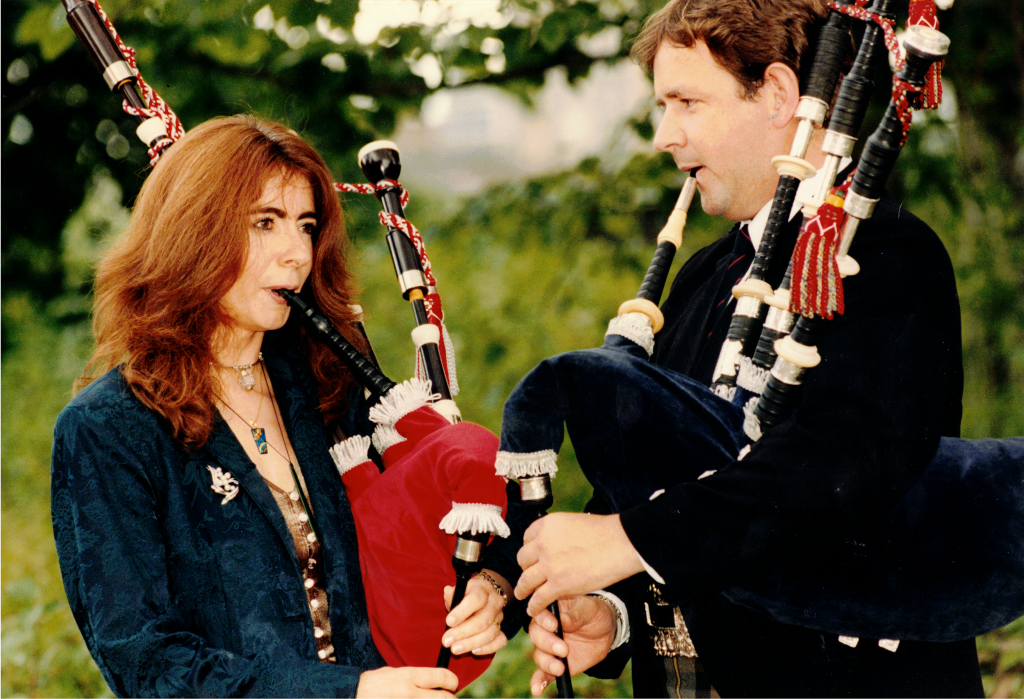 Evelyn playing the bag pipes with another piper in the 1990s